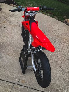 a red dirt bike parked on top of a sidewalk