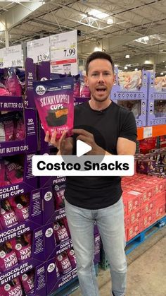 a man standing in front of purple and pink boxes with the words costo snacks on it