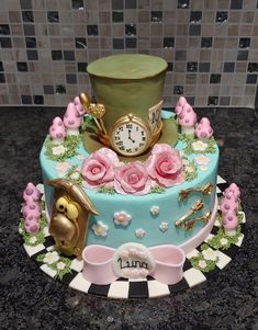 a cake decorated with pink flowers and a top hat on a table next to a tile wall