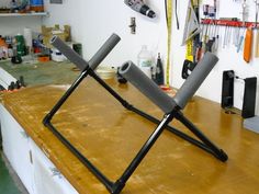 two chairs sitting on top of a wooden table in a room with tools hanging from the wall