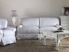 a white couch and chair in a room with wooden floors, two lamps on either side of the couch