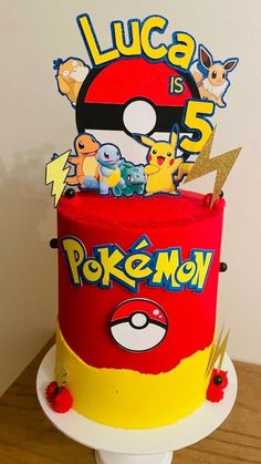 a red and yellow cake with pokemon characters on the top is sitting on a table