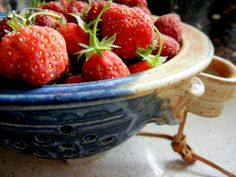 a blue bowl filled with lots of ripe strawberries