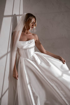 a woman in a wedding dress leaning against a wall