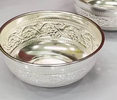 two silver bowls sitting next to each other