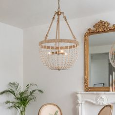 a chandelier hanging from the ceiling in a living room with two chairs and a fireplace