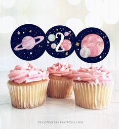 three cupcakes with pink frosting and planets on them are shown in front of a white background