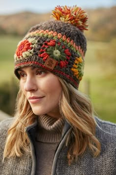 a woman wearing a knitted hat with pom - poms