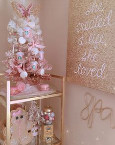 a pink and gold christmas tree in a room with some decorations on the shelf next to it