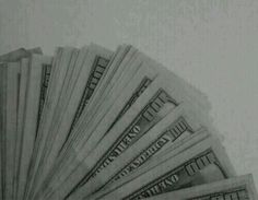 a stack of twenty dollar bills sitting on top of each other in front of a white wall