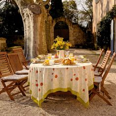 a table set with food and flowers in front of an old stone building on a sunny day