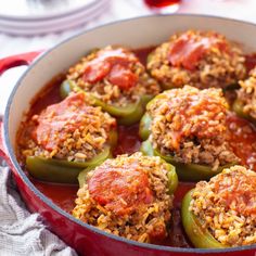 stuffed peppers with meatballs and sauce in a red pan on a white tablecloth