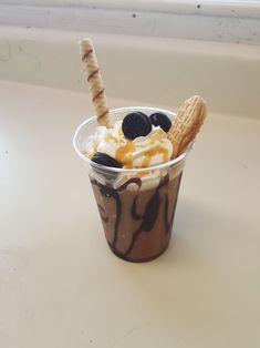 an ice cream sundae topped with cookies and oreo slices in a plastic cup