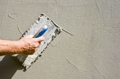 a man is holding a paint roller in his hand and painting the exterior of a house