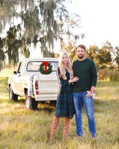 a man and woman standing in front of a truck with a christmas wreath on it