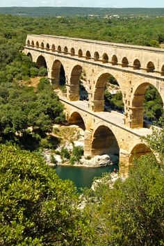 an old stone bridge over a river surrounded by trees