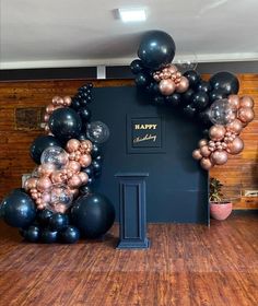 black and gold balloons are arranged in the shape of a happy birthday arch