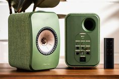 two green speakers sitting on top of a wooden table