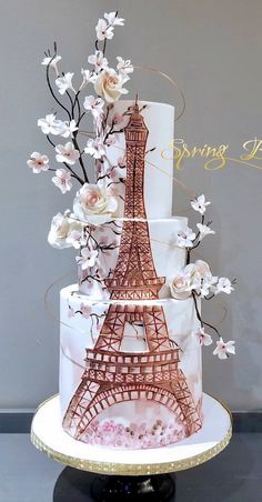 a three tiered cake decorated with flowers and the eiffel tower in paris