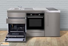 a white kitchen with an oven, sink and dishwasher on the floor next to a brick wall