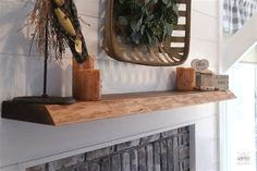 a mantel with candles and wreaths on it in front of a wall mounted fireplace