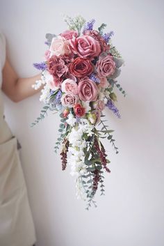 a bridal holding a bouquet of pink and white flowers in it's hand