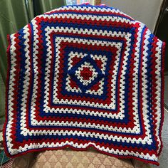 a red, white and blue crocheted blanket sitting on top of a chair