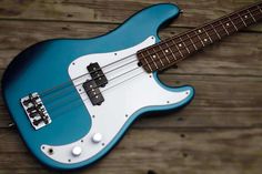 a blue and white bass guitar sitting on top of a wooden floor