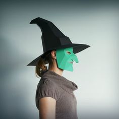 a woman wearing a paper mask with a witch's hat on top of her head