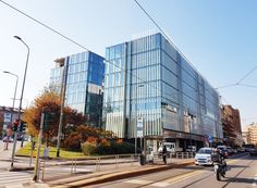 an office building on the corner of a street with cars and motorcycles driving down it