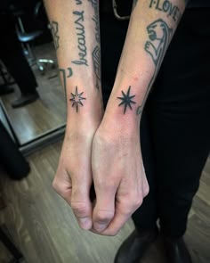 two people holding hands with tattoos on their arms and one has a star tattoo on the wrist