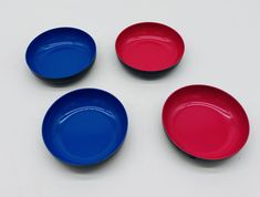 three red and one blue plates on a white surface