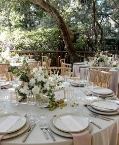 the table is set with white plates and silverware for an elegant wedding reception in the woods