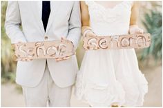 a man and woman holding up two wooden signs that say welcome to someone on their wedding day