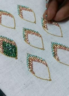 someone is working on beading with gold and green beads