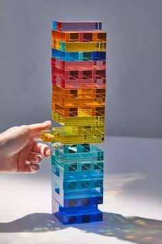 a hand is reaching for a stack of colorful plastic blocks that are stacked on top of each other