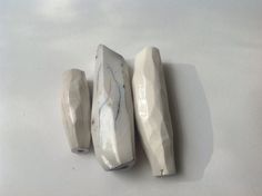 three pieces of white marble sitting on top of a table