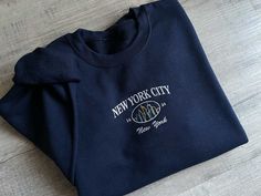 "\"New York City \" embroidered on a cute vintage-style crewneck. A cozy sweatshirt bound to keep you warm in the colder months. A pre-shrunk, classic fit sweater that's made with air-jet spun yarn for a soft feel and reduced pilling. Your new favorite sweatshirt! SIZING: * Sizing is unisex * Runs true to size * For an oversized look we suggest to size up 1 to 2 sizes PRODUCT DETAILS: * 100% cotton face * 65% cotton, 35% polyester * Self-fabric patch on the back * Designed and printed in the USA Please note that the embroidery comes with a backing that acts as a stabilizer to support the fabric and stitches. CARE INSTRUCTIONS: Machine wash cold, inside out, gentle cycle with similar colors recommended. Tumble dry low, or hand dry for longest life. *Due to different monitor screens, colors Cozy Crew Neck Sweatshirt With Letter Embroidery, New York Crewneck, New York Sweatshirt, New York Vintage, Vintage New York, Sweatshirt Vintage, Embroidered Sweater, Embroidered Sweatshirt, Fabric Patch