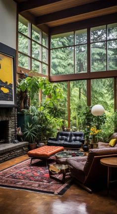 a living room filled with furniture and lots of windows overlooking the trees in the forest