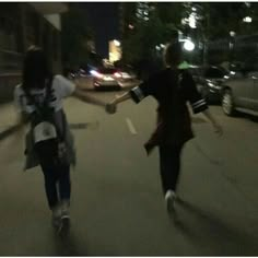 two girls are running down the street at night