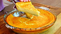 a person cutting into a cheesecake in a glass pie dish on a wooden table