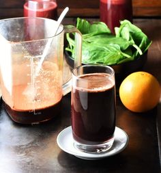 there is a pitcher of liquid next to a glass and some oranges on the table