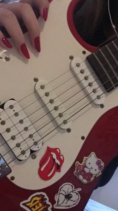 a woman with red nail polish holding an electric guitar