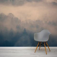 a white chair sitting on top of a wooden floor next to a wall covered in fog