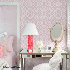 a bedroom with pink and white wallpaper, a gold desk lamp and a bed