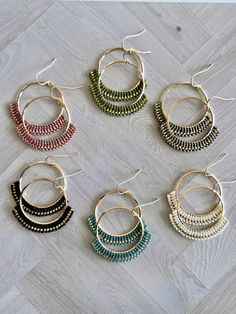 six pairs of multicolored beaded hoop earrings sitting on a wooden floor next to each other