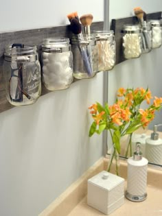 mason jars are lined up on the wall to hold makeup brushes and other personal care items