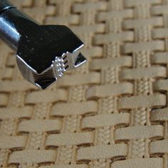 a small black object sitting on top of a tan cloth covered tablecloth with woven weaves