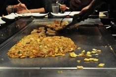 some food is being prepared on a large metal tray with chopsticks in it