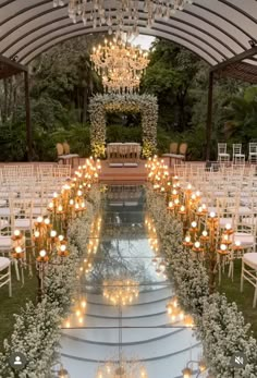 an outdoor wedding venue with white chairs and chandeliers